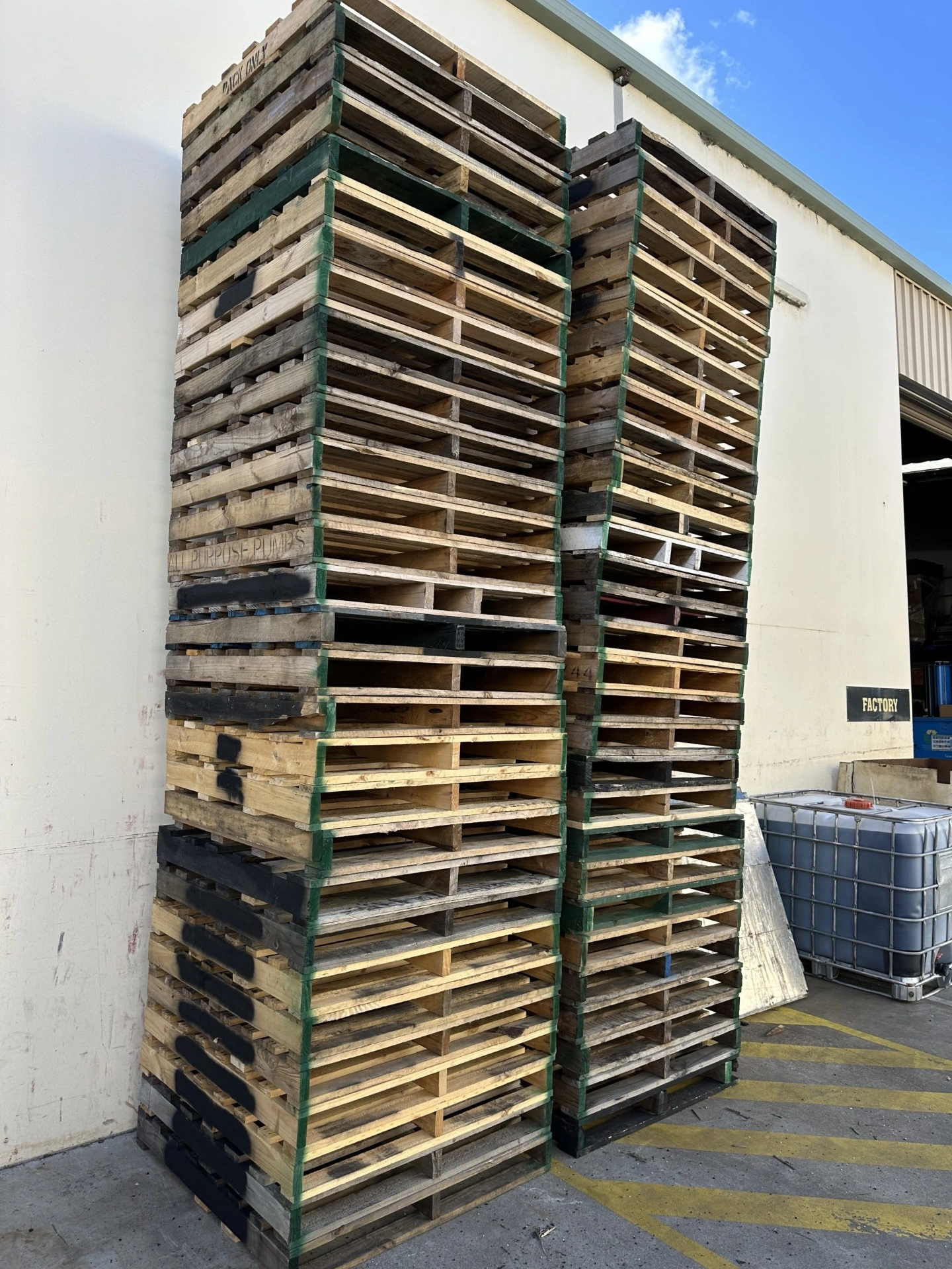 Tall stacks of repaired pallets outside the factory